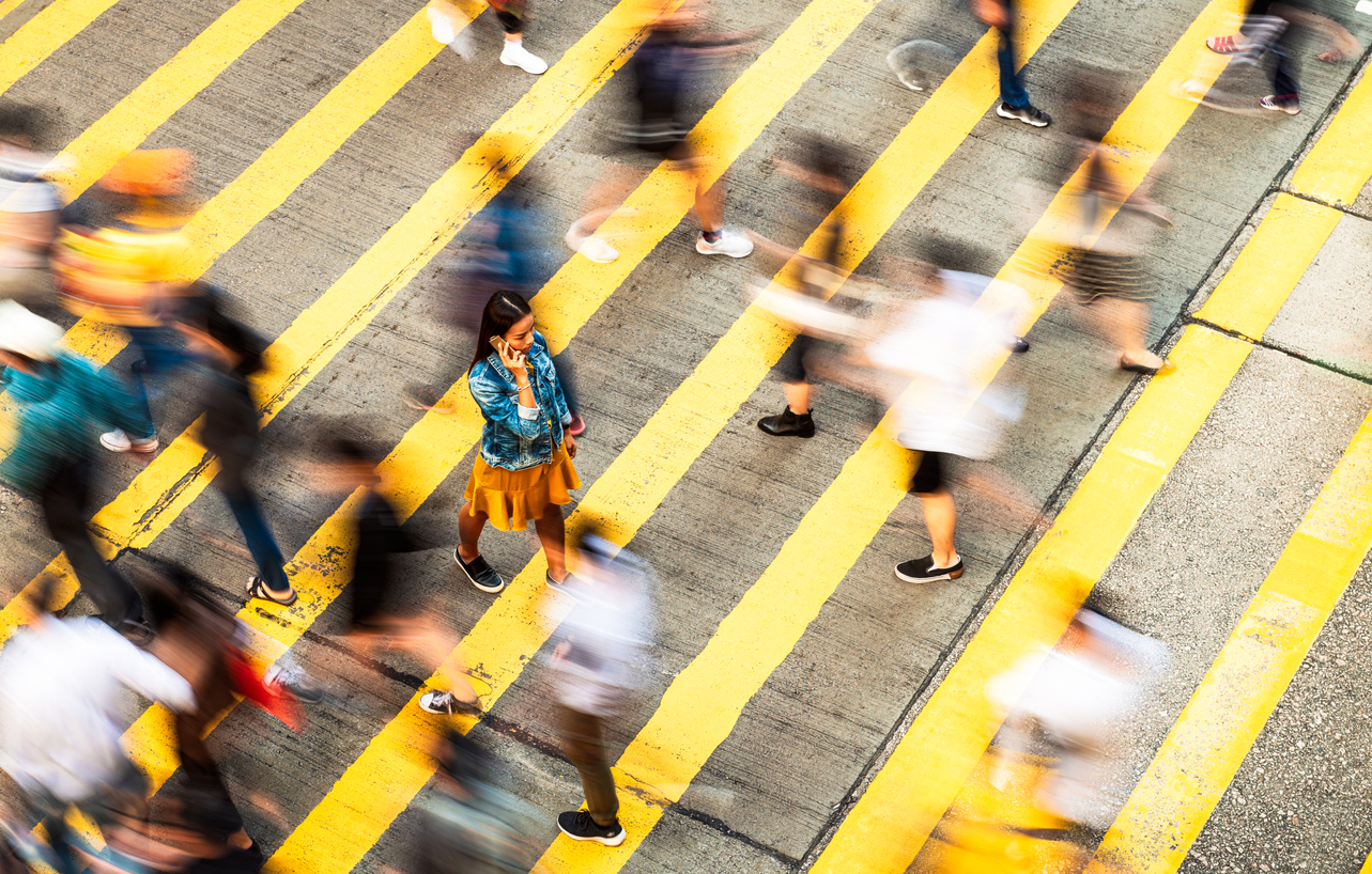A person walking across a street with a group of people walking, illustrating Bi-Modal IT where organisations manage two distinct work styles, and Digital Transformation, reflecting the evolving landscape of business and technology integration.